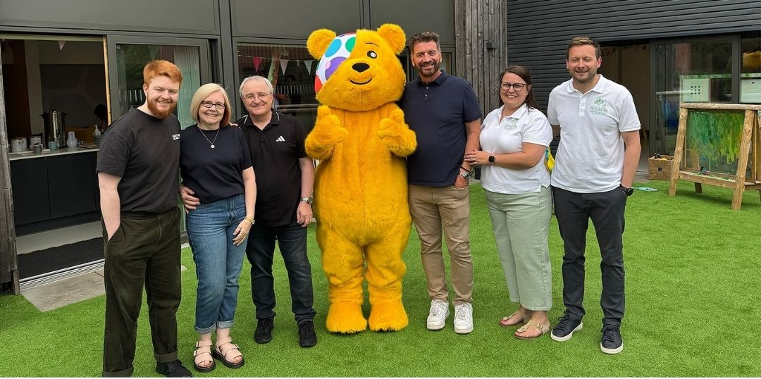 Pudsey the bear with the DIY SOS team outside of a newly built wellness centre for The Joshua Tree